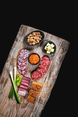 Dry meat and sausages with vegetables and cheese on a wooden table