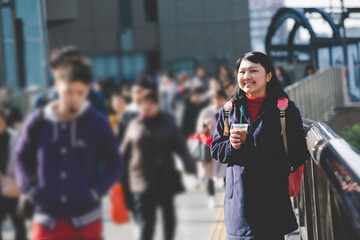 Travelers holding a cup of coffee stand watch Osaka Umeda district on the overpass with happiness in winter.