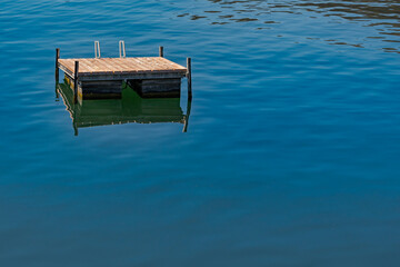 Minimalist photo of wooden platform for sunbathing and for swimmers on the swiss lake of  Lugano