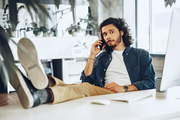 Casually dressed young businessman using mobile phone in office