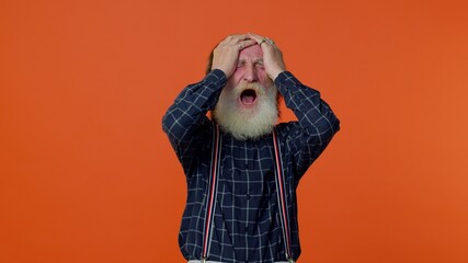 Elderly bearded frustrated man screams from stress tension problems feels horror hopelessness fear surprise shock expresses gestures rage. Senior old grandfather on orange background. People emotions