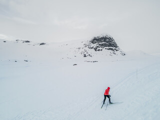 Fototapeta na wymiar Cross country skier traveling across a snowy arctic tundra in the high mountains on a cold winters day.