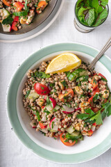 Flat-lay of two bowls with healthy vegan wholewheat pearl couscous salad on a white background, with copy space