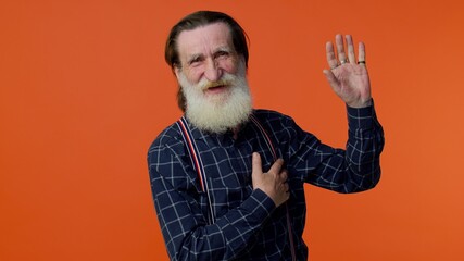 I swear to be honest. Sincere responsible senior old bearded gray-haired man raising hand to take oath, promising to be honest and to tell truth, keeping hand on chest. Elderly grandfather pensioner