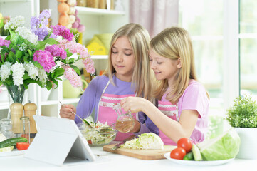 Two girls in pink aprons preparing salad