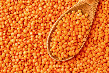 Wooden spoon and red lentils top view close up