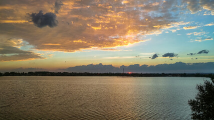 Sunset over the lake with beautiful clouds illuminated by the rays of the setting sun