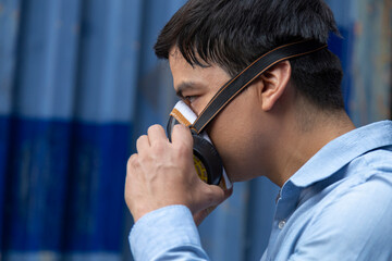 young businessman wearing half mask respirator to protect the coronavirus or covid-19 pandemic and pm2.5 bad air pollution from traffic and manufacturing industrials in the city.