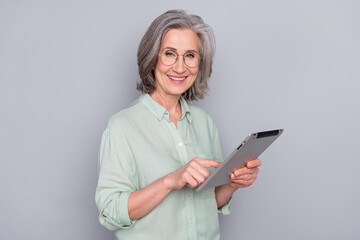 Photo of happy smiling cheerful lovely mature businesswoman in glasses work in tablet isolated on...