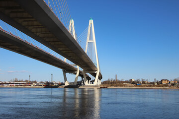 Fototapeta premium View of the cable-stayed bridge pylons and a fragment of the highway with reflexes in the water for a thematic banner