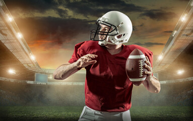 American football sportsman player with ball in action on stadium under lights of background. Sport, proud footballer in white helmet and red t-shirt ready to play.