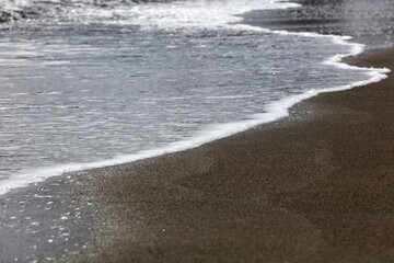 soft waves with white foam come ashore at sunset