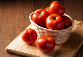 Tomatoes, beautiful tomatoes arranged in a basket and on wood, dark background, selective focus.