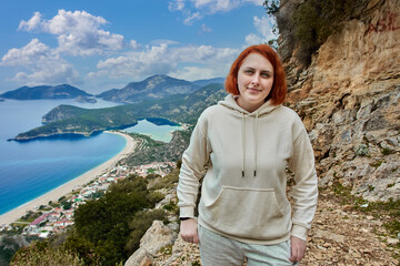 Lycian Trail in Blue Lagoon area of Oludeniz village near Fethiye, young white woman with red hair poses against backdrop of landscape.