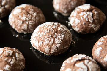 Cracked chocolate cookies with icing sugar on a pan