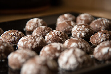 Cracked chocolate cookies with icing sugar on a pan
