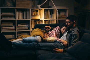 young couple watching television at home. evening scene