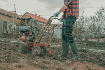 Farmer performing garden tillage with an old motor cultivator