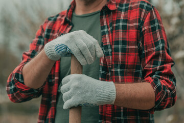 Farmer holding a spade shaft, resting in the garden during gardening work