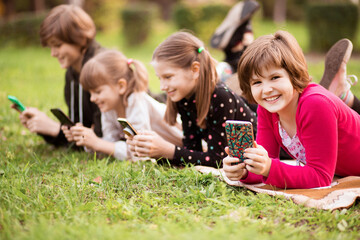Outdoor portrait of little girls and boys playing with phones . High quality photo
