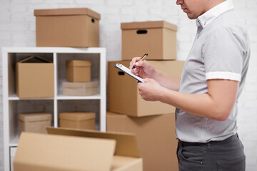 work and business concept - close up of male hands writing something in clipboard in warehouse