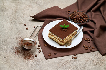 Portion of Traditional Italian Tiramisu dessert and coffee beans on grey concrete background