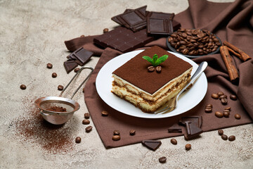 Portion of Traditional Italian Tiramisu dessert and coffee beans on grey concrete background