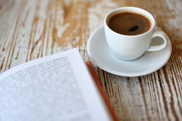Сup of coffee and a book on table