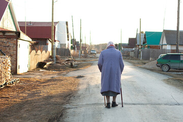 The grandmother is walking down the road in the village. Lonely old age. caring for the elderly. Social advertising