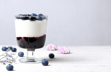 Creamy dessert with blueberries in a glass on a white table with copy space