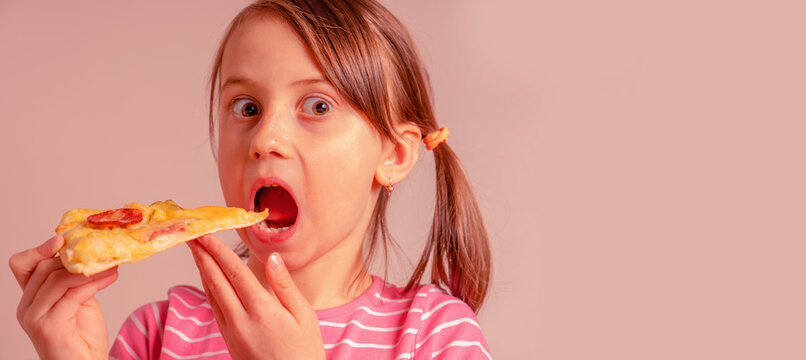 It's really delicious! Young girl is eating a piece of pizza. Selective focus on eyes. Copy space for deswign.