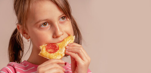 It's really delicious! Happy beautiful young girl is eating a piece of pizza.  Copy space for design or text.