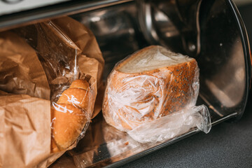 bread in plastic bags in a breadbox, metal bread bin  - obrazy, fototapety, plakaty