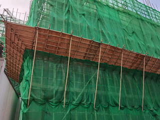 Building wrapped in traditional Chinese scaffolding made of bamboo for worker to repair or replace air conditioner above window outside high rise or the entire building in Hong Kong © James Jiao