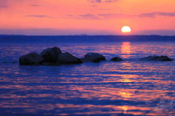 Fototapeta na wymiar stones in lake water on sunset