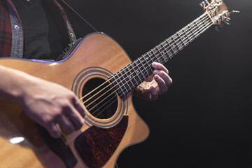Fototapeta na wymiar Guitarist playing acoustic guitar in the dark.
