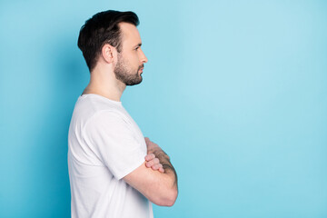 Profile photo of young person folded arms look attentively empty space isolated on blue color...
