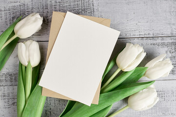 Fototapeta na wymiar Greeting card mockup with white tulip flowers on rustic wooden background