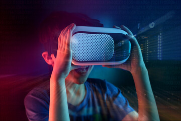 boy, child in dark room with neon lights in modern VR glasses interacting with network while having virtual reality experience, concept study of another world, modern teaching technologies