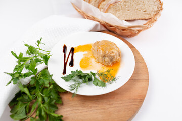 Meatballs with gravy garnished with herbs on a white background