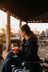 Young woman with a glass of red wine, outdoors, at a rustic winery terrace.