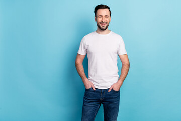 Portrait of attractive cheerful experienced guy expert holding hands in pockets isolated over blue bright pastel color background