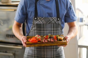 Freshly cooked meat and grilled vegetables. Ready food on a wooden board.