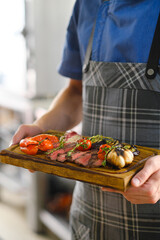Freshly cooked meat and grilled vegetables. Ready food on a wooden board.
