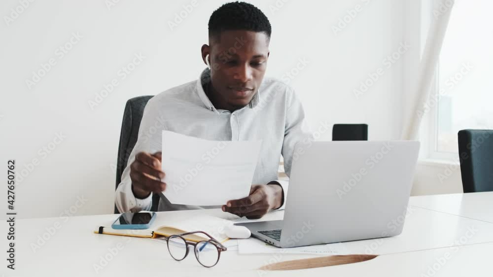 Sticker A handsome black guy with earbuds is talking with video-connection using this laptop sitting in the office