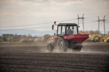 Fototapeta premium Tractor spreading artificial fertilizers