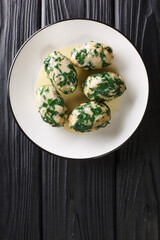 Spinach and Cheese Breadcrumb Dumplings Strangolapreti close-up in a plate on the table. Vertical top view from above