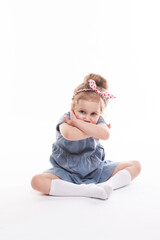 Childhood, emotions concept, little cute girl in a blue dress posing in the studio on a white