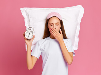 Sleepy woman showing alarm clock