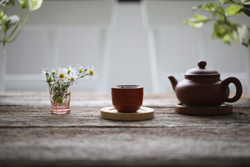oriental teapot and tea cup with daisy flower on wooden table